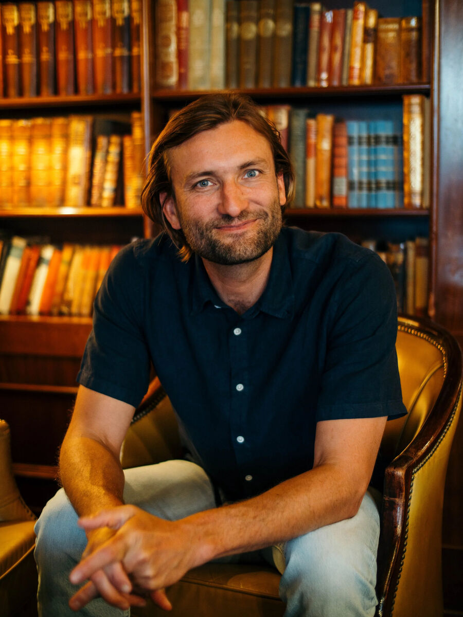 Smilende mann sitter framoverlent i stol