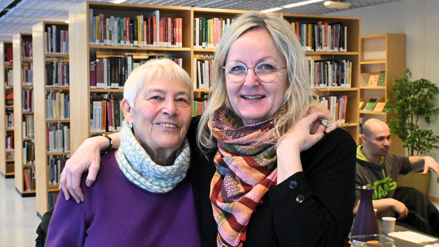 Portrett av to damer som smiler og står tett