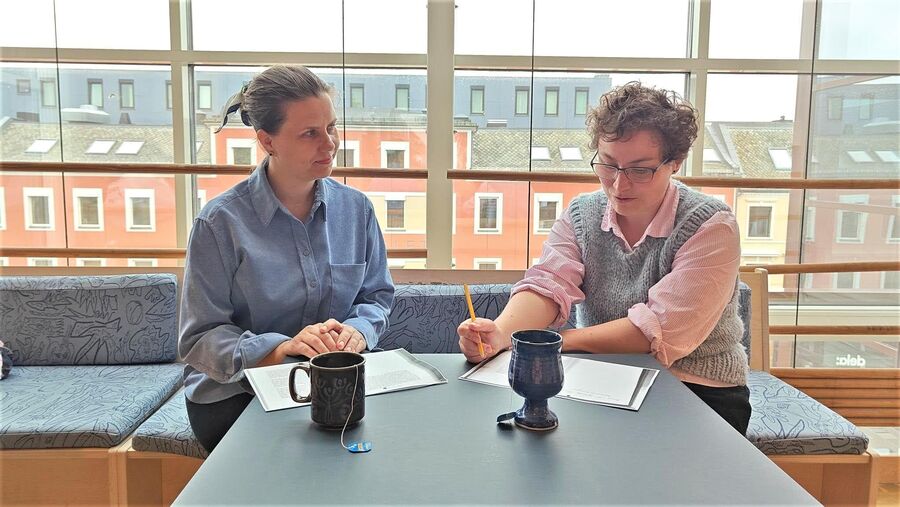 Konseptet er hentet fra England, og metoden heter shared reading. To kvinner sitter ved et bord, leser tekst sammen.