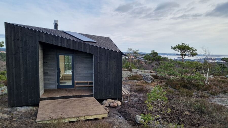 Øyliblikk i Vågsbygd har en storslått utsikt og ligger i et flott turområde. (Foto: Midt-Agder friluftsråd) Hytte på heia med havet i bakgrunnen