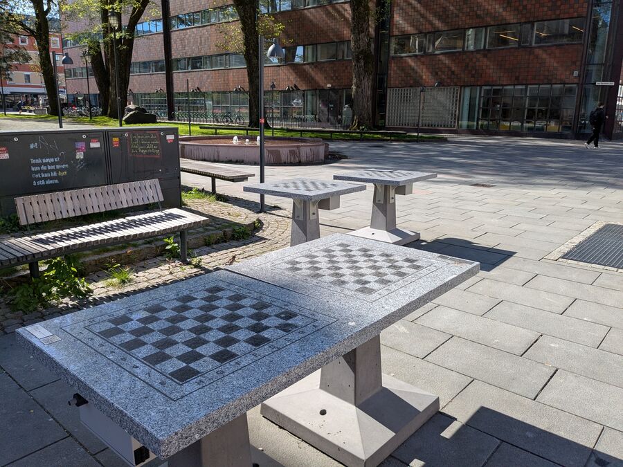 Utenfor hovedbiblioteket står det fire sjakkbord. Brikker kan du låne i barneavdelingen. (Foto: Reidar Bjorvatn) Bord og benker utendørs
